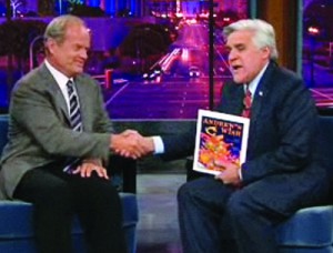 A person wearing a suit and tie reading a book, with Jay Leno