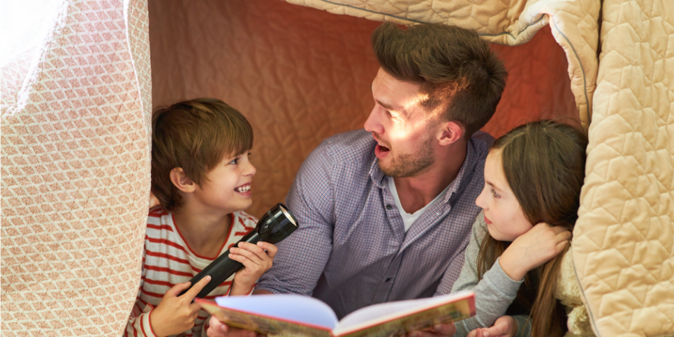 dad and kids reading with flashlight