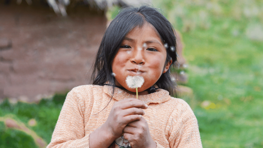 Native American Girl blowing the seeds of a dandelion.