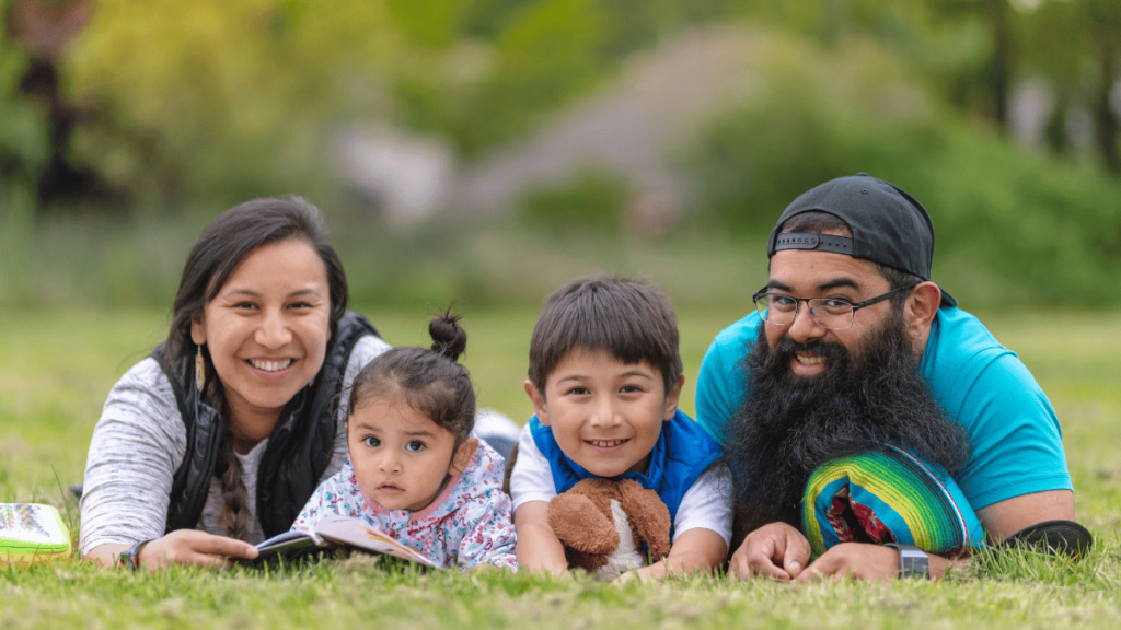 Native American Family, laying in grass reading together.