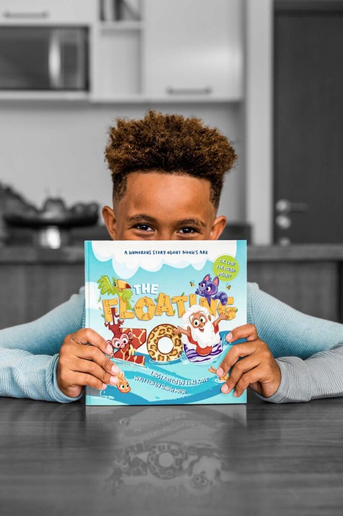 A young boy holding a copy of The Floating Zoo.