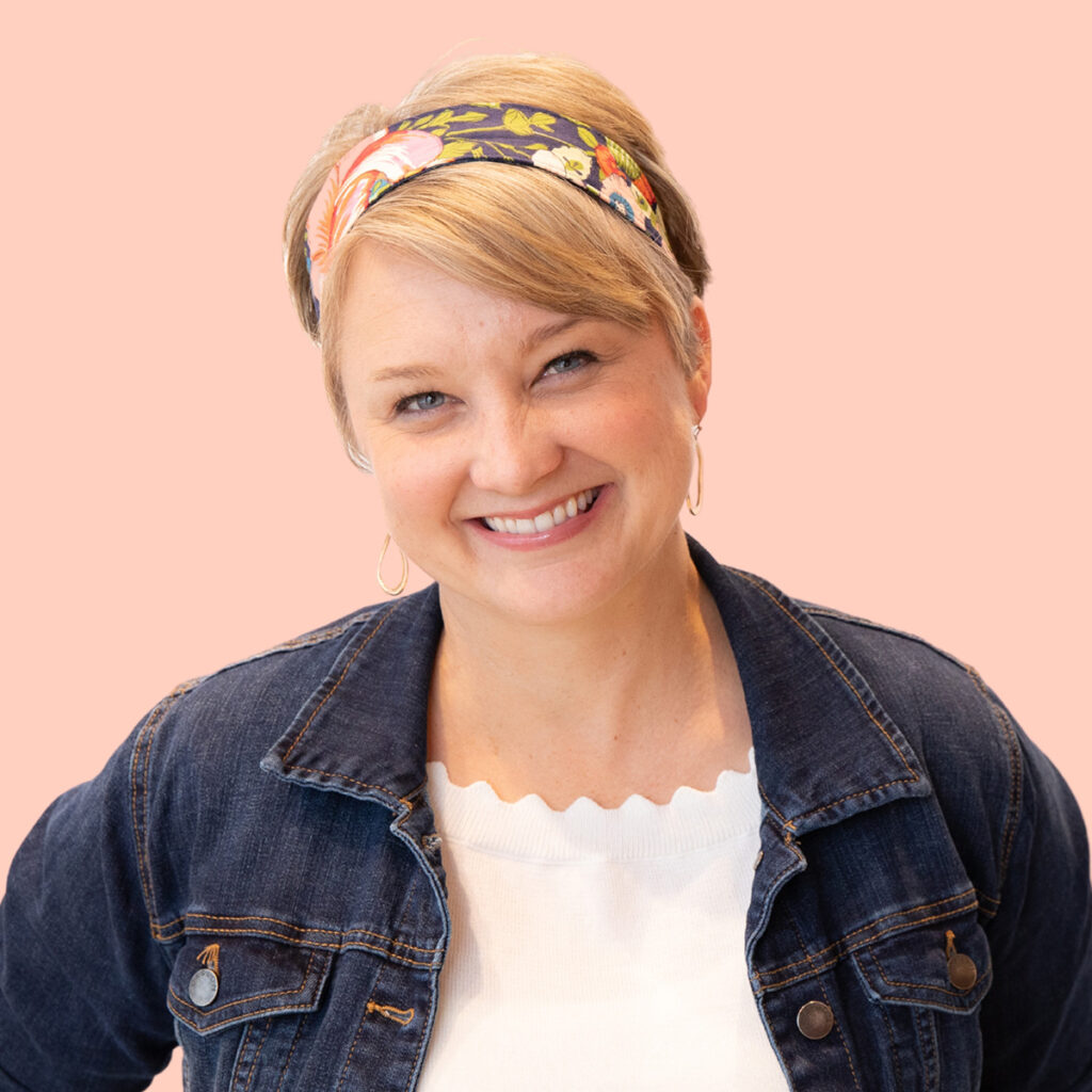 Sarah Mackenzie: Author Headshot. Wearing a floral headband. Pink background.