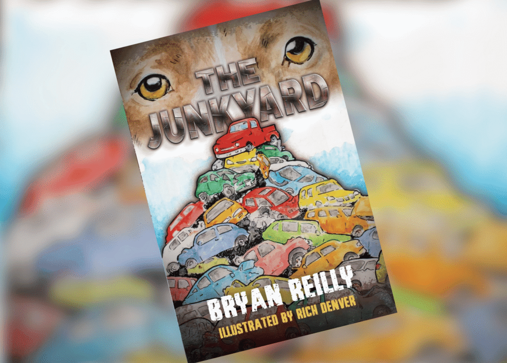 The Junkyard Header | The Children's Book Review Book cover titled 'The Junkyard' showing a pile of colorful cars with a large pair of eyes in the background; illustrated by Rich Denver; author Bryan Reilly.